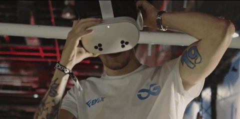 Hombre con gafas de realidad virutal con mandos PlayStation en evento deportivo y tecnológico