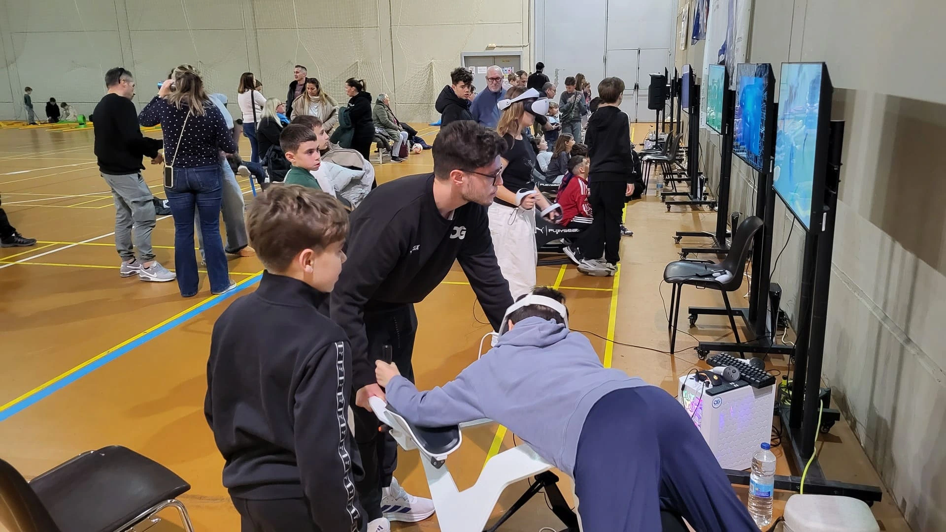 Niños probando simulador de conducción PC durante un evento deportivo de Oxygen Gaming